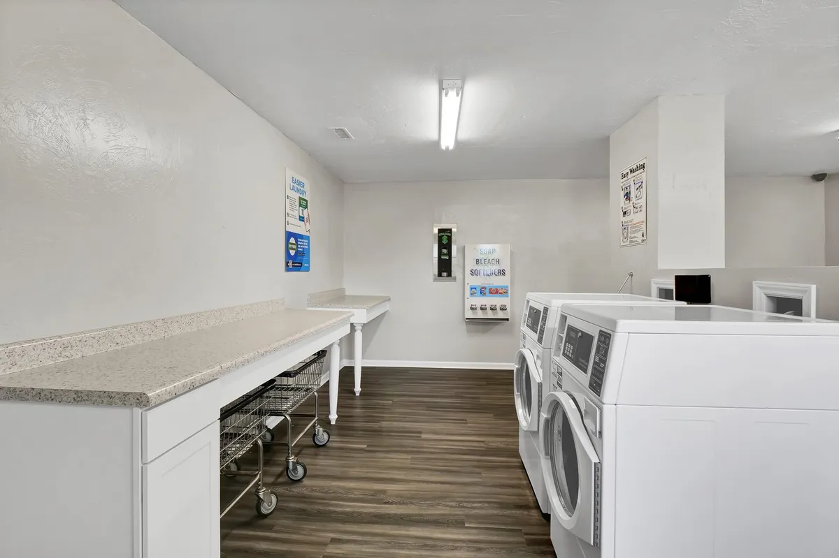 A bright, organized laundry room with modern washing machines, dryers, and a folding counter, designed to serve the community’s residents. The space is practical and communal, ensuring guests have easy access to laundry facilities.