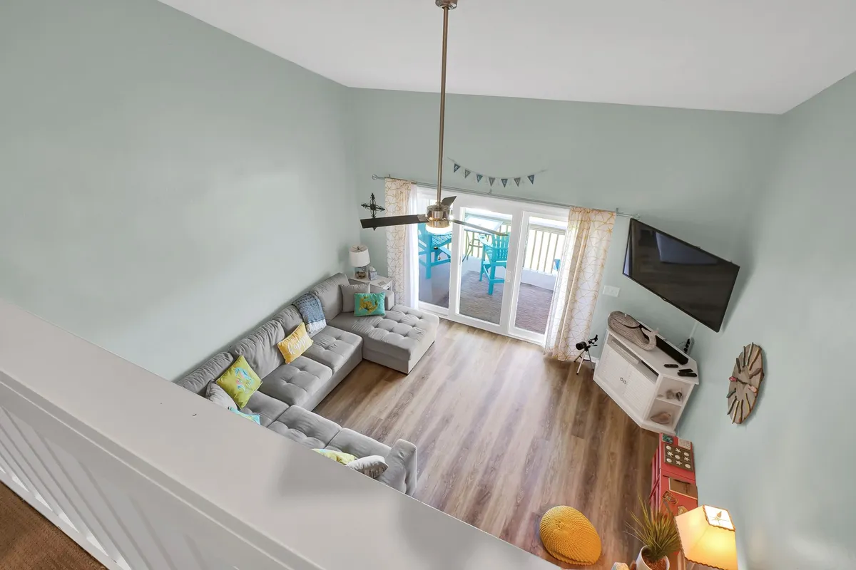 An inviting living room features a comfortable sofa, coffee table, TV, and doors leading to a balcony. The space is bathed in natural light, perfect for relaxing, socializing, or watching TV together, with the balcony providing a seamless connection to the outdoors.